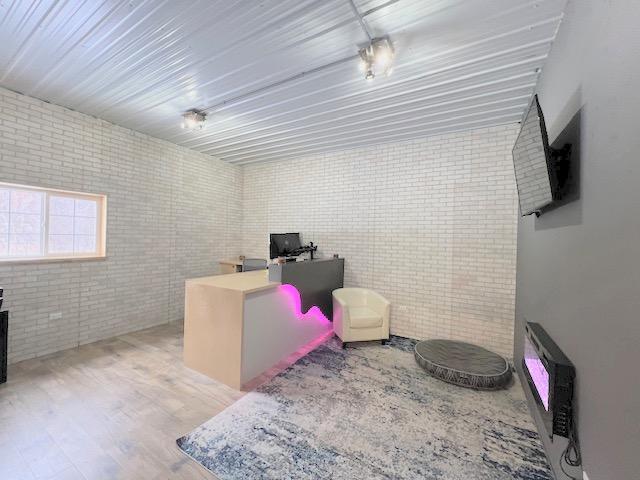 home office featuring wood-type flooring and brick wall