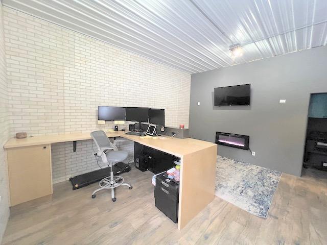 office area featuring built in desk, light hardwood / wood-style flooring, and brick wall