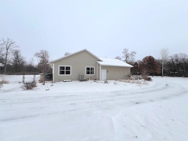 snow covered house featuring central AC