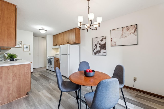 dining room with light hardwood / wood-style floors, an inviting chandelier, and sink