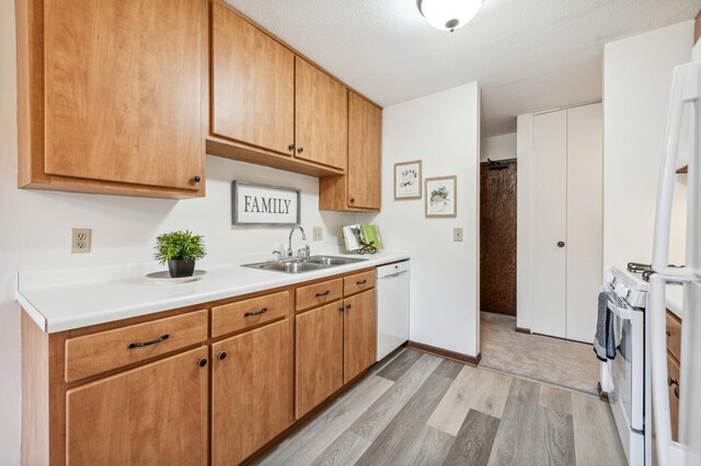 kitchen featuring a textured ceiling, sink, light hardwood / wood-style floors, and white appliances