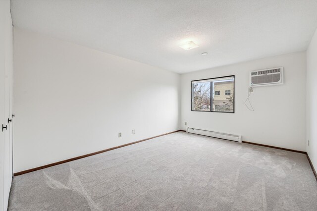 carpeted spare room featuring a textured ceiling, an AC wall unit, and baseboard heating