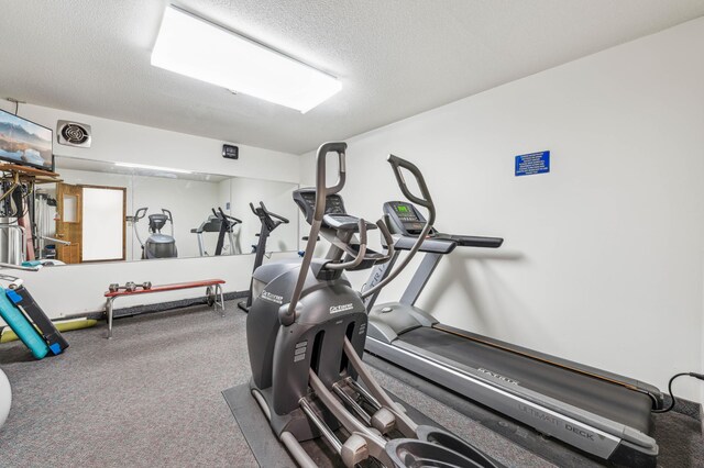 workout area with carpet flooring and a textured ceiling