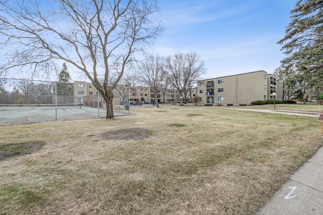 view of property's community with a yard and tennis court