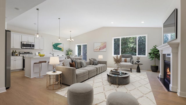 living room with a chandelier, light wood-type flooring, lofted ceiling, and sink