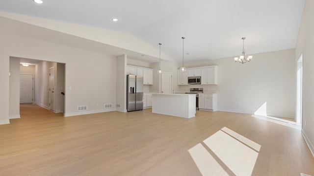 unfurnished living room with an inviting chandelier, light hardwood / wood-style floors, and vaulted ceiling