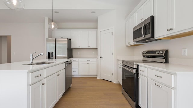 kitchen featuring pendant lighting, white cabinets, sink, light wood-type flooring, and appliances with stainless steel finishes