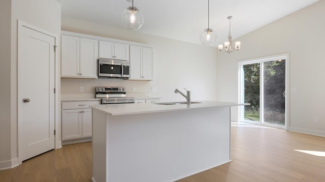 kitchen with a kitchen island with sink, white cabinets, sink, appliances with stainless steel finishes, and decorative light fixtures