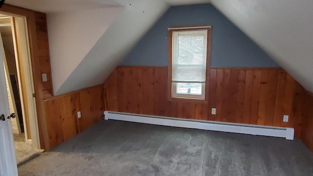 additional living space featuring a healthy amount of sunlight, lofted ceiling, baseboard heating, and wooden walls