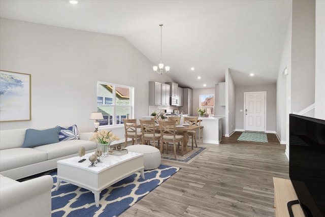 living room featuring high vaulted ceiling, light hardwood / wood-style floors, and an inviting chandelier