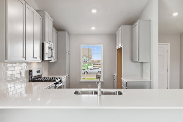 kitchen with decorative backsplash, kitchen peninsula, sink, and appliances with stainless steel finishes