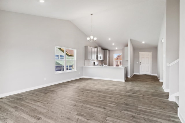 unfurnished living room featuring dark hardwood / wood-style flooring, high vaulted ceiling, and an inviting chandelier