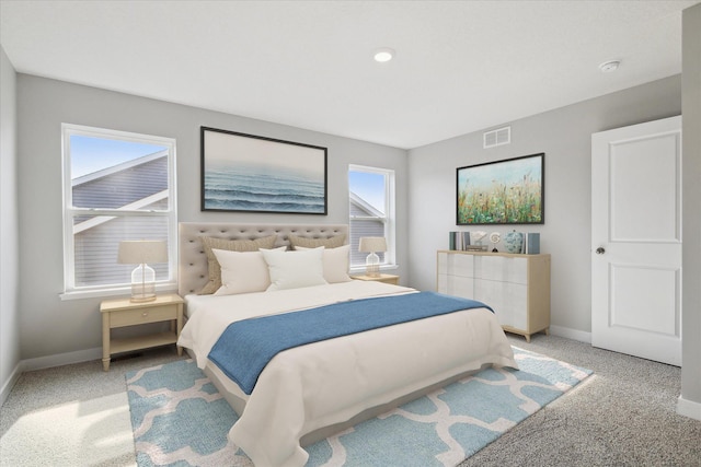 bedroom with light colored carpet and multiple windows