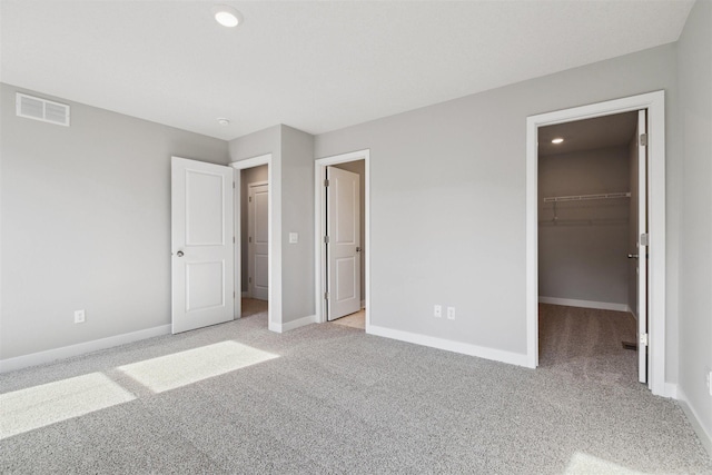 unfurnished bedroom featuring a walk in closet, light carpet, and a closet