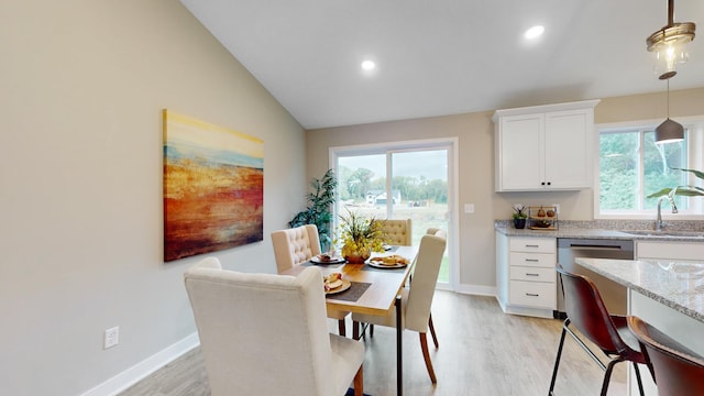 dining room with light hardwood / wood-style floors, lofted ceiling, and sink