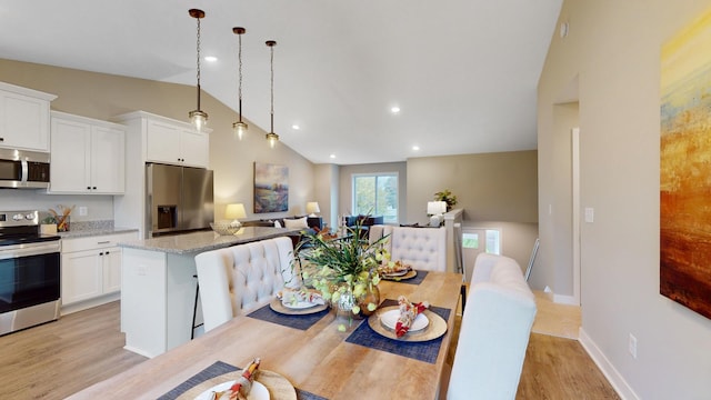 dining area featuring light wood-type flooring and lofted ceiling