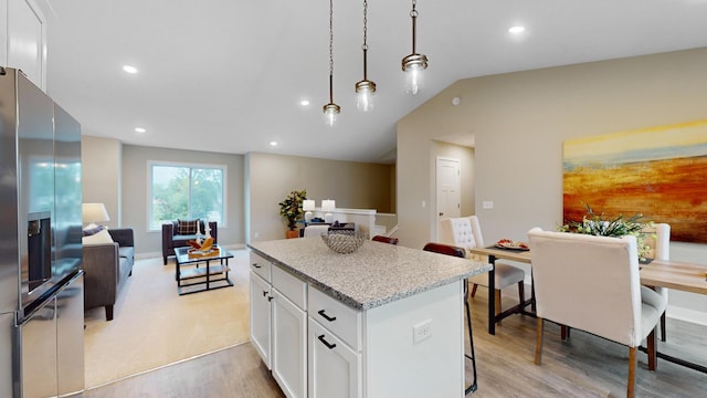 kitchen with white cabinets, stainless steel fridge with ice dispenser, a center island, and light wood-type flooring