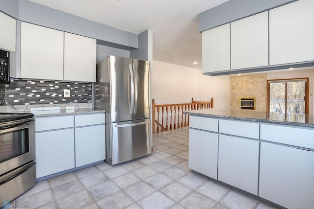 kitchen featuring tasteful backsplash, white cabinets, stainless steel appliances, and stone countertops