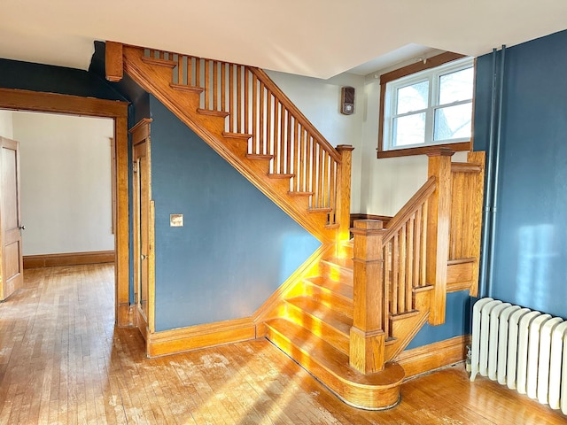 stairway featuring radiator heating unit and hardwood / wood-style flooring