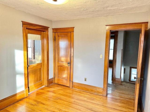 unfurnished bedroom with a textured ceiling and light hardwood / wood-style flooring