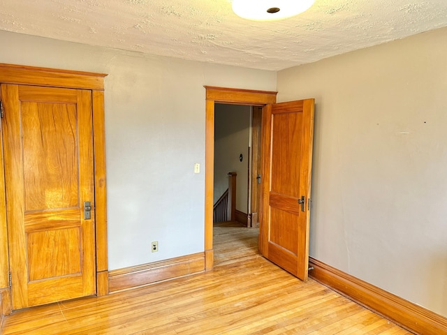 unfurnished room featuring light hardwood / wood-style floors and a textured ceiling