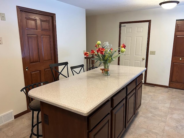 kitchen featuring a kitchen breakfast bar, dark brown cabinetry, and a kitchen island