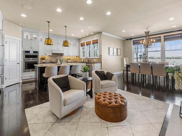 living room featuring sink, light wood-type flooring, a wealth of natural light, and a textured ceiling