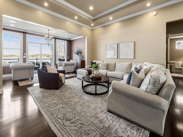 living room with dark wood-type flooring, ornamental molding, and a chandelier