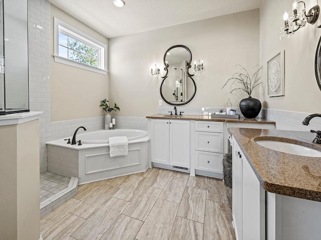 bathroom with vanity, a textured ceiling, and shower with separate bathtub