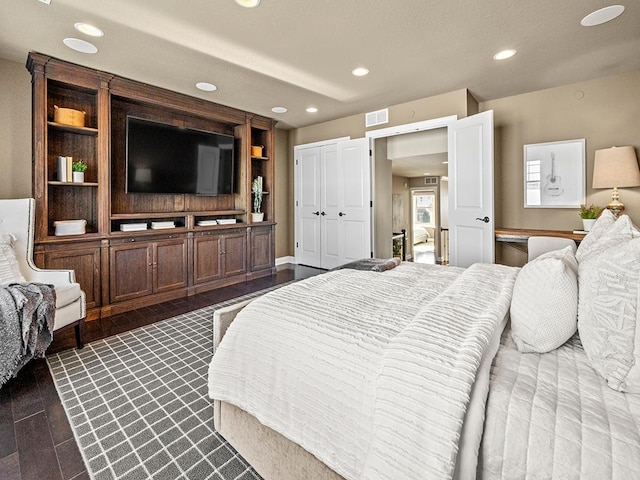 bedroom with dark hardwood / wood-style floors and a closet