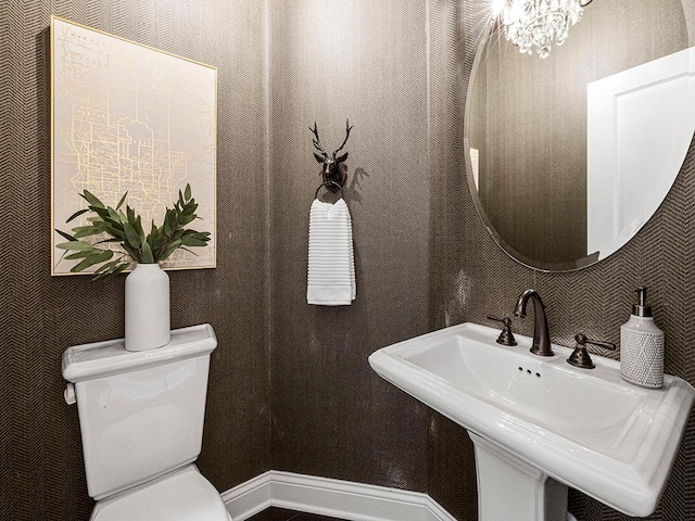 bathroom featuring toilet, sink, and an inviting chandelier