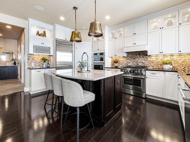 kitchen featuring high end appliances, a kitchen island, and white cabinetry