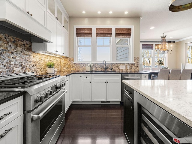 kitchen with white cabinets, sink, custom range hood, and high end stainless steel range oven