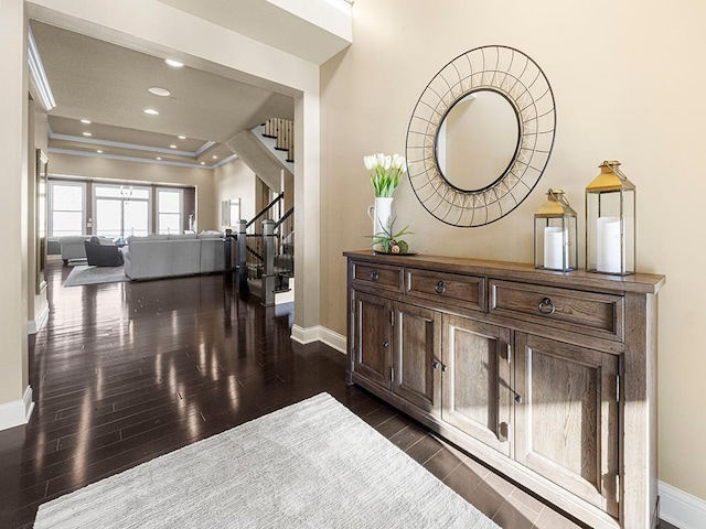 hall featuring a raised ceiling, dark hardwood / wood-style flooring, and ornamental molding