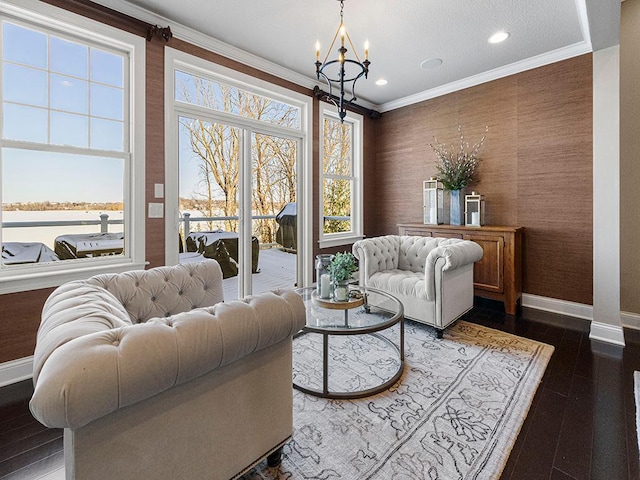 living area featuring a water view, an inviting chandelier, crown molding, and dark hardwood / wood-style floors