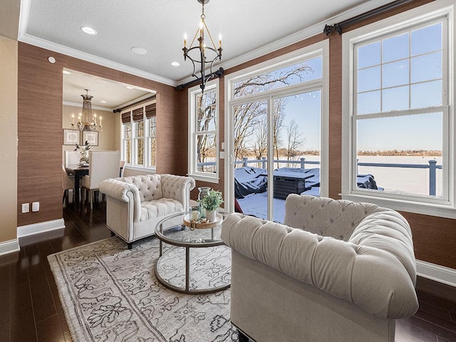 living room featuring dark hardwood / wood-style floors, a water view, a notable chandelier, and ornamental molding