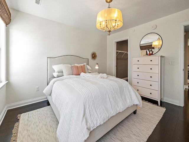 bedroom featuring dark wood-type flooring, a chandelier, a closet, and a spacious closet