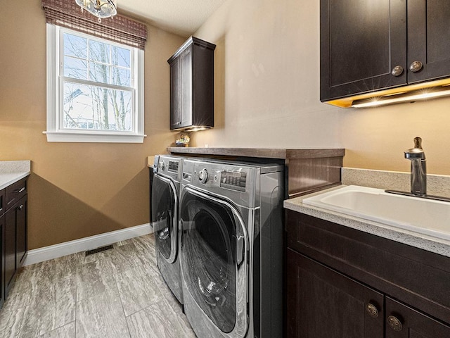 laundry room featuring washing machine and dryer, sink, and cabinets