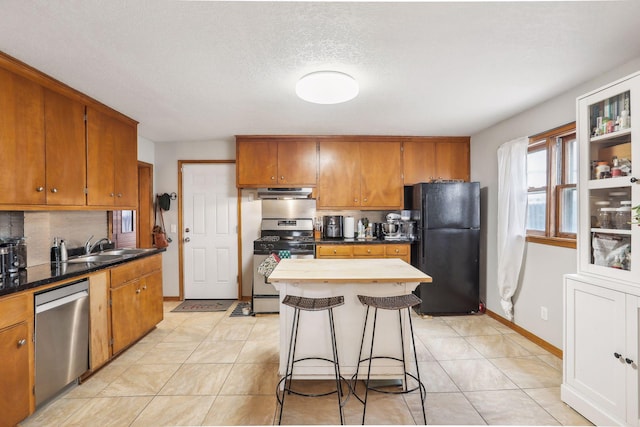 kitchen featuring a kitchen bar, sink, light tile patterned flooring, and stainless steel appliances