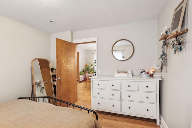 bedroom with light hardwood / wood-style floors and a textured ceiling