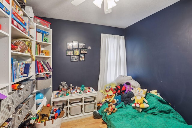 bedroom with ceiling fan, wood-type flooring, and a textured ceiling