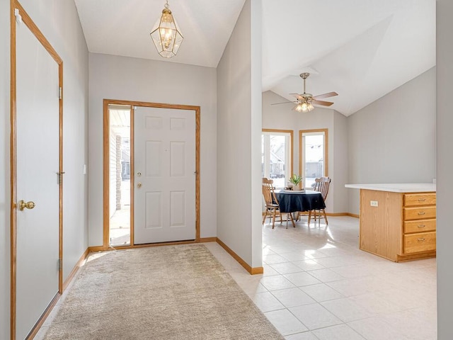 entryway featuring ceiling fan with notable chandelier, vaulted ceiling, and light tile patterned flooring