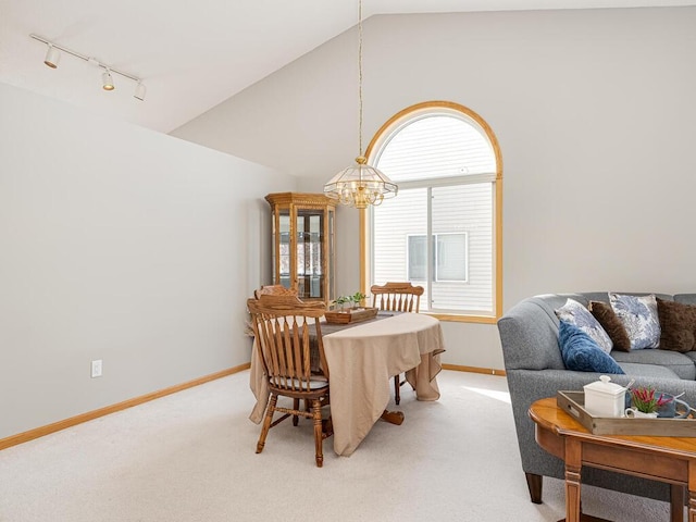 carpeted dining room with vaulted ceiling, rail lighting, and a notable chandelier