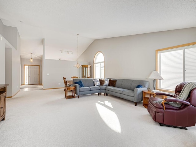 carpeted living room with an inviting chandelier, a healthy amount of sunlight, and vaulted ceiling