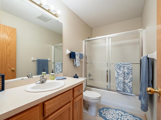 full bathroom featuring toilet, bath / shower combo with glass door, a textured ceiling, vanity, and tile patterned flooring