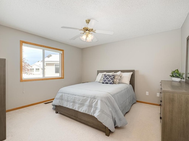 carpeted bedroom with ceiling fan and a textured ceiling