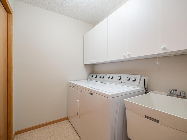 laundry area with sink, a textured ceiling, cabinets, and washing machine and clothes dryer