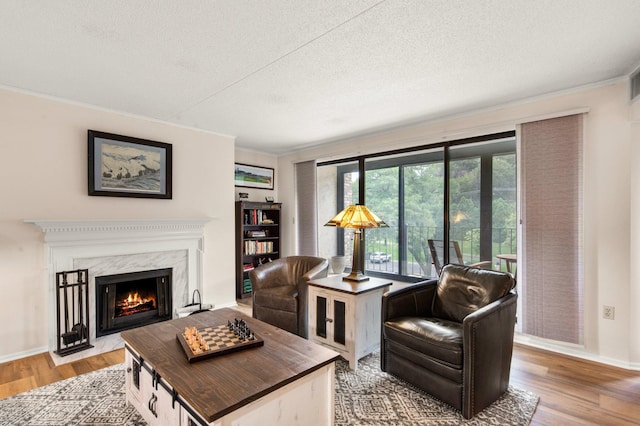 living room with a high end fireplace, a textured ceiling, light hardwood / wood-style floors, and crown molding