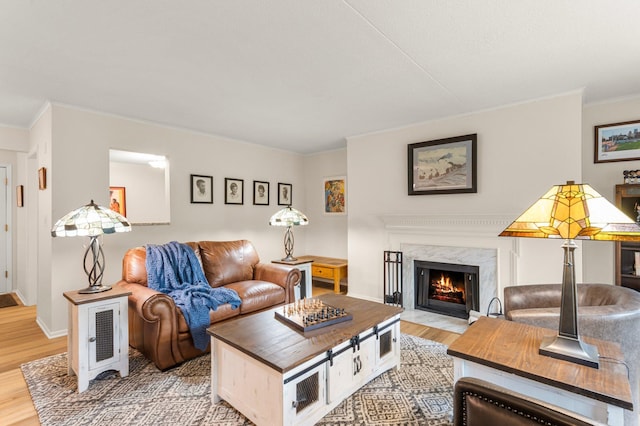 living room featuring light hardwood / wood-style floors, a premium fireplace, and ornamental molding