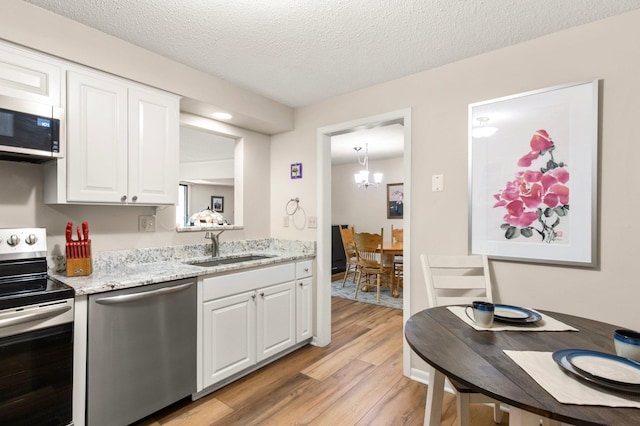 kitchen featuring a textured ceiling, white cabinetry, sink, and appliances with stainless steel finishes